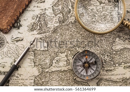Compass, ink pen, magnifier and folder on vintage map