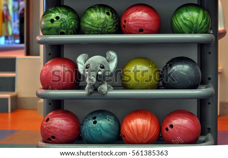 Toy elephant between bowling balls.