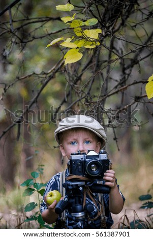 Stylish small boy with retro camera photographing outdoors on sunny autumn day
