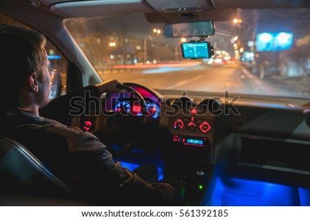 The man drive a car in the night city. Inside view