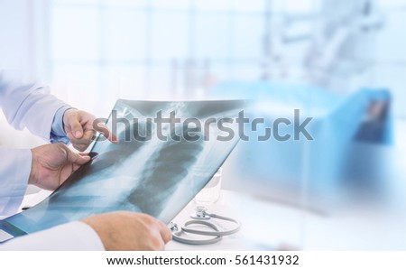 Doctor examining at lungs radiograph x-ray film of patient in operation room. medical concept. Royalty-Free Stock Photo #561431932