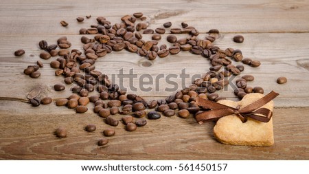 Frame- heart from coffee beans and two cookies-heart related together on wooden table    