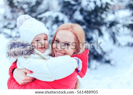 Mother and child girl having fun, playing and laughing on snowy winter walk in nature. 