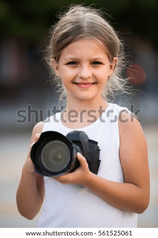 girl holding modern photo camera in hands outdoors
