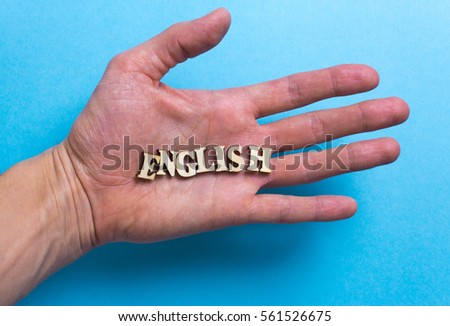 The word of English of wooden letters of the alphabet on the hand on a blue background