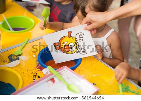 A child draws with colored sand picture. Cartoon characters.