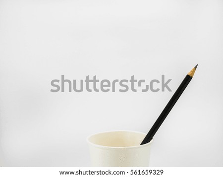 Black pencil in paper cup on white background.