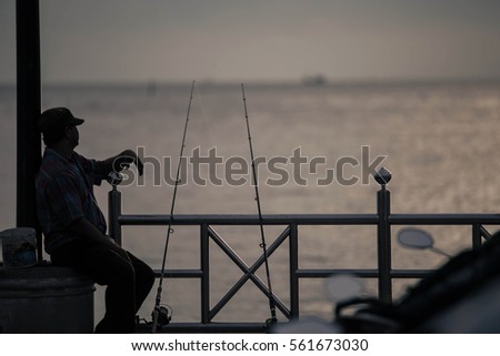 Silhouette picture of fisherman fishing at the sea on sunset. The lifestyle concept background.