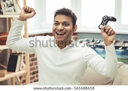 Attractive Afro American man is smiling while playing game console at home