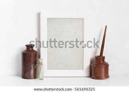 Empty white wooden frame and inkstands on the white table