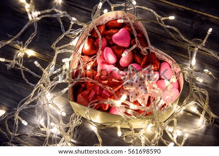 The concept of Valentine's Day with a garland and gift box in the shape heart on wooden background.