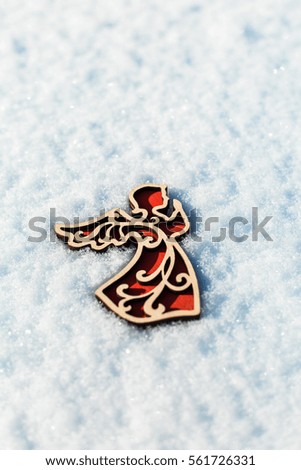 Red wooden toy angel on white snow