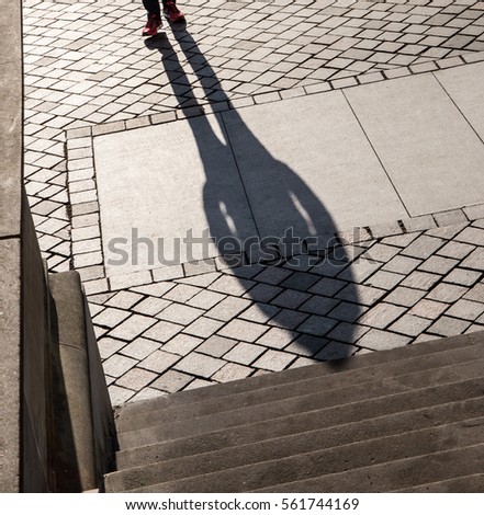 The shadow of a pedestrian can be seen on the cobbled street of a street