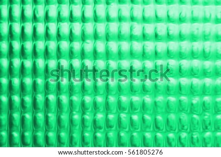 Abstract background of blurred dotted textured semi transparent glass bluish green color