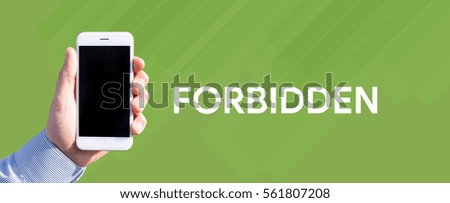 Smart phone in hand front of green background and written FORBIDDEN