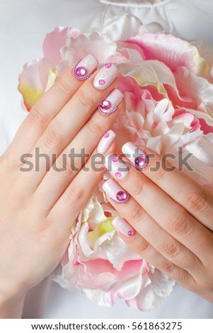 Closeup photo of a beautiful female hands with pink nail art design manicure and flower.
