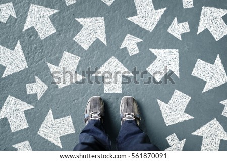 Taking decisions for the future man standing with many direction arrow choices, left, right or move forward Royalty-Free Stock Photo #561870091