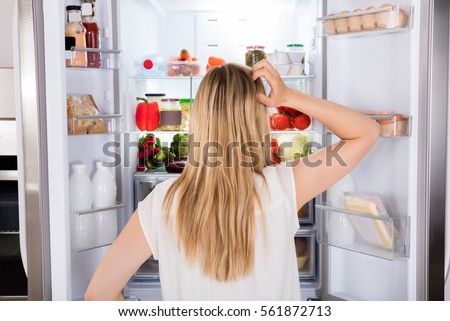 Rear View Of Young Woman Looking In Fridge At Kitchen Royalty-Free Stock Photo #561872713