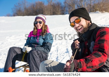 Happy young couple sledding down the hill