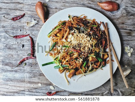 Healthy Vegetarian/vegan menu; Padthai noodle with smoke tofu and mixed vegetable - sprout, carrot, garlic chive, shallot and radish) with crushed peanut, sunflowers,  pumpkin seeds and dried raisin Royalty-Free Stock Photo #561881878