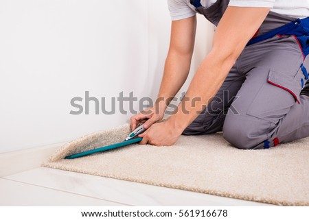 Close-up Of A Craftsman Fitting Carpet On Floor With Cutter Royalty-Free Stock Photo #561916678