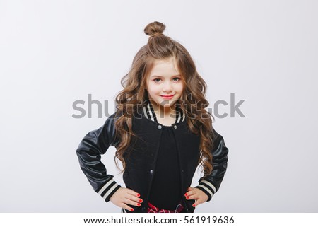 portrait of little modern model in studio. Curly hairstyle, fashion clothes