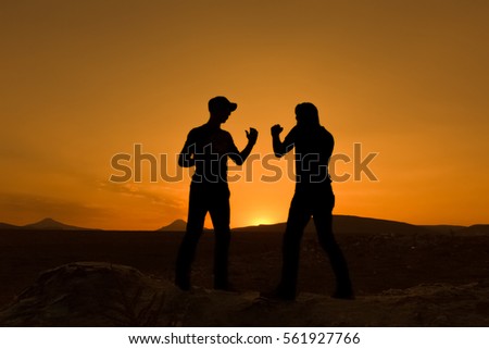 young men fighting over skyline at sunset background