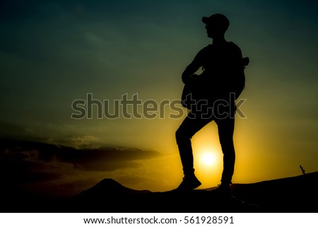 young man with a guitar skyline at sunset background