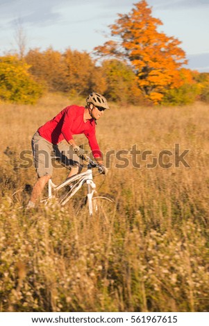 Man rides a mountain bike on single track trail during the autumn