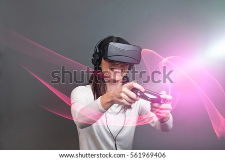 Casual young woman sitting and having fun playing a virtual reality video game against a dark background