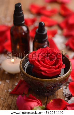 Spa setting with red rose, petals on old wooden board
