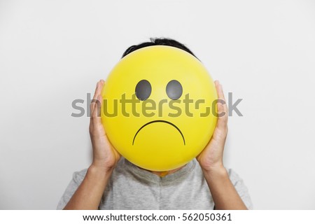 A man holding a yellow balloon with sad face emotion instead of head Royalty-Free Stock Photo #562050361