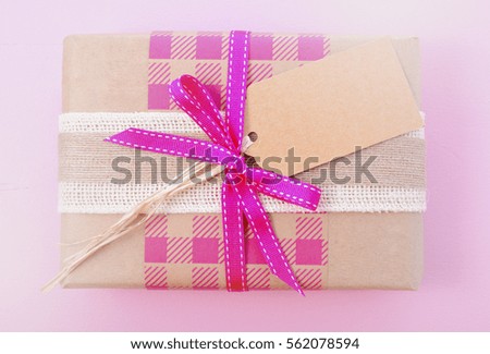 Vintage style wrapped pink gifts in kraft paper and old newspaper for Valentines Day, with applied white vignette filters.
