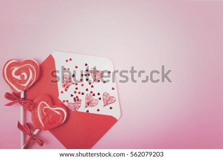 Happy Valentines Day opened love letter envelope  with red heart shape lollipop on pink wood background, with applied vintage style filters.