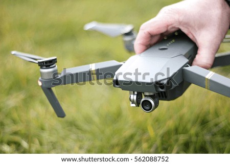 A person holding their drone over grass