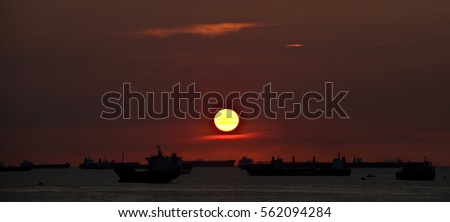 Sunrise sunset on the coast South China sea ocean horizon with liner trawler tanker cruise ships sail boats in orange yellow glow reflection cloud formation scattering blue sky