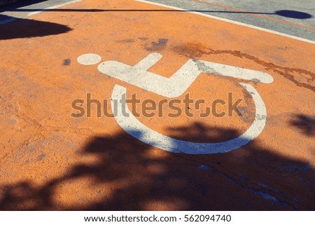 white wheelchair handicap road sign painted on a orange pavement