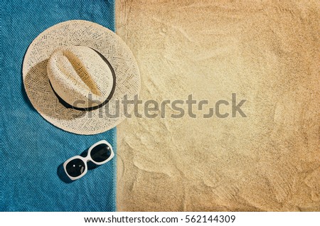 Top view of sandy beach with towel frame and summer accessories. Background with copy space and visible sand texture. Left border made of towel