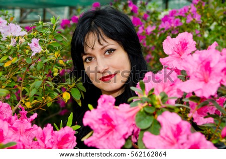 Cute young brunette posing on the background of blooming azaleas.