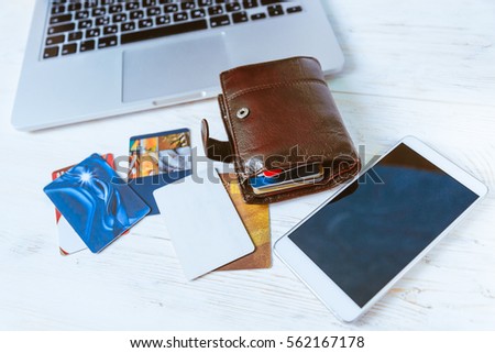 laptop wallet glasses bank cards phone on wooden table