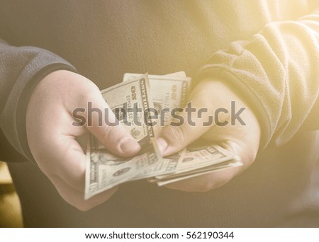 Man with money us dollars in hands. Male cutting cash. Vintage style retro toned picture in warm tones