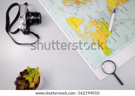 Magnifying Glass, world map, plane and vintage camera. Top view photo.