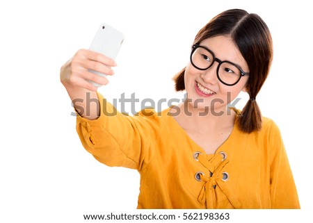 Young happy Asian woman smiling while taking selfie picture with mobile phone