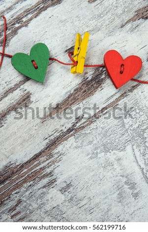 Valentine's day concept. Red and green wooden heart and clothespin on a wood background.