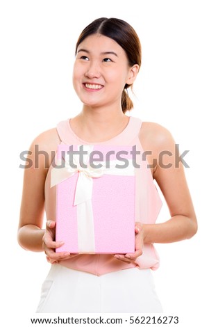 Thoughtful young happy Asian woman smiling and holding gift box ready for Valentine's Day