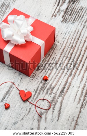Valentines day vintage background with hearts and a red gift box on wooden board