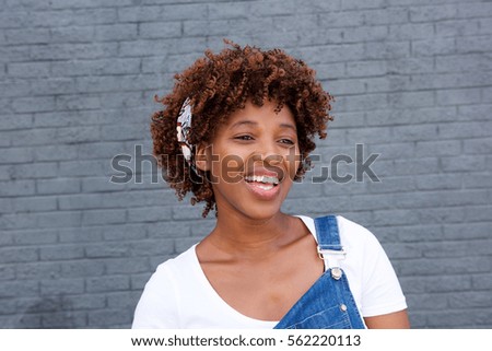 Close up portrait of african woman laughing against gray wall