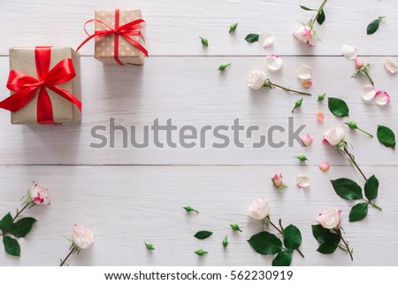 Valentine background with pink rose flowers frame and gift boxes with copy space on white rustic wood. Happy lovers day presents mockup