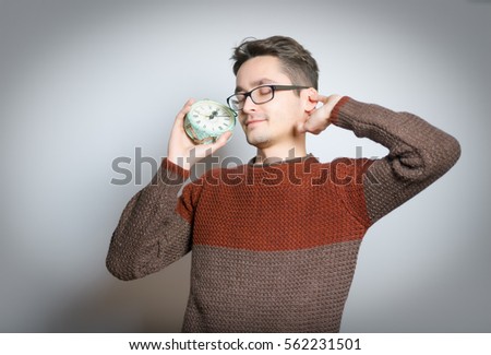 Handsome man yawning with an alarm clock, isolated on background