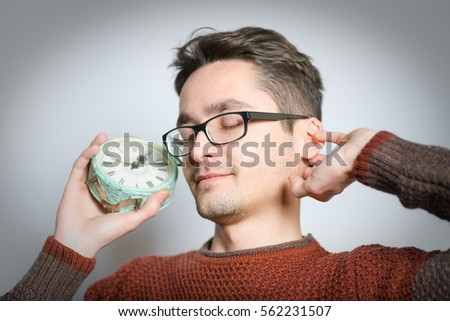 Handsome man yawning with an alarm clock, isolated on background